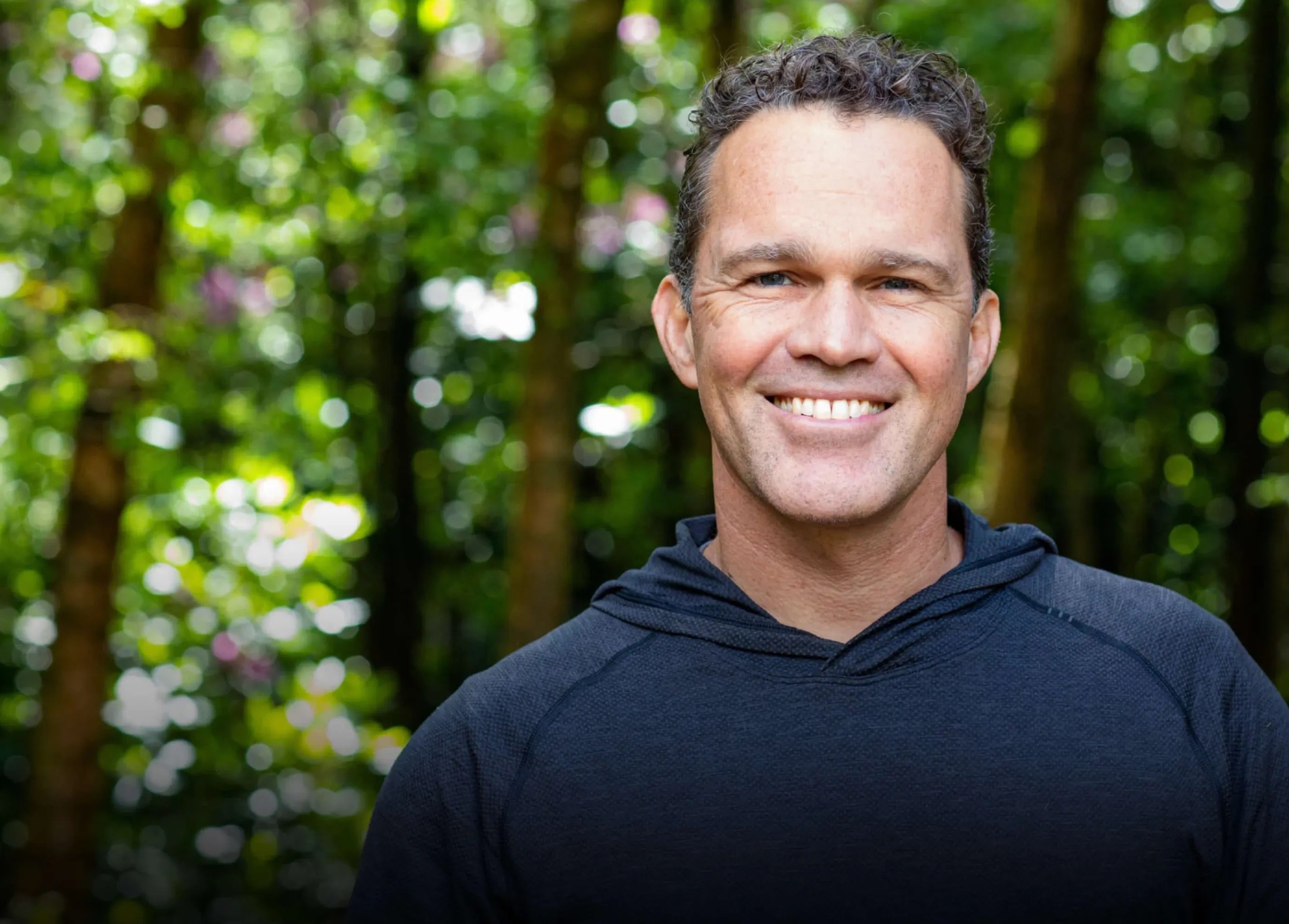 Zach Bush standing in a forest with greenery in the background